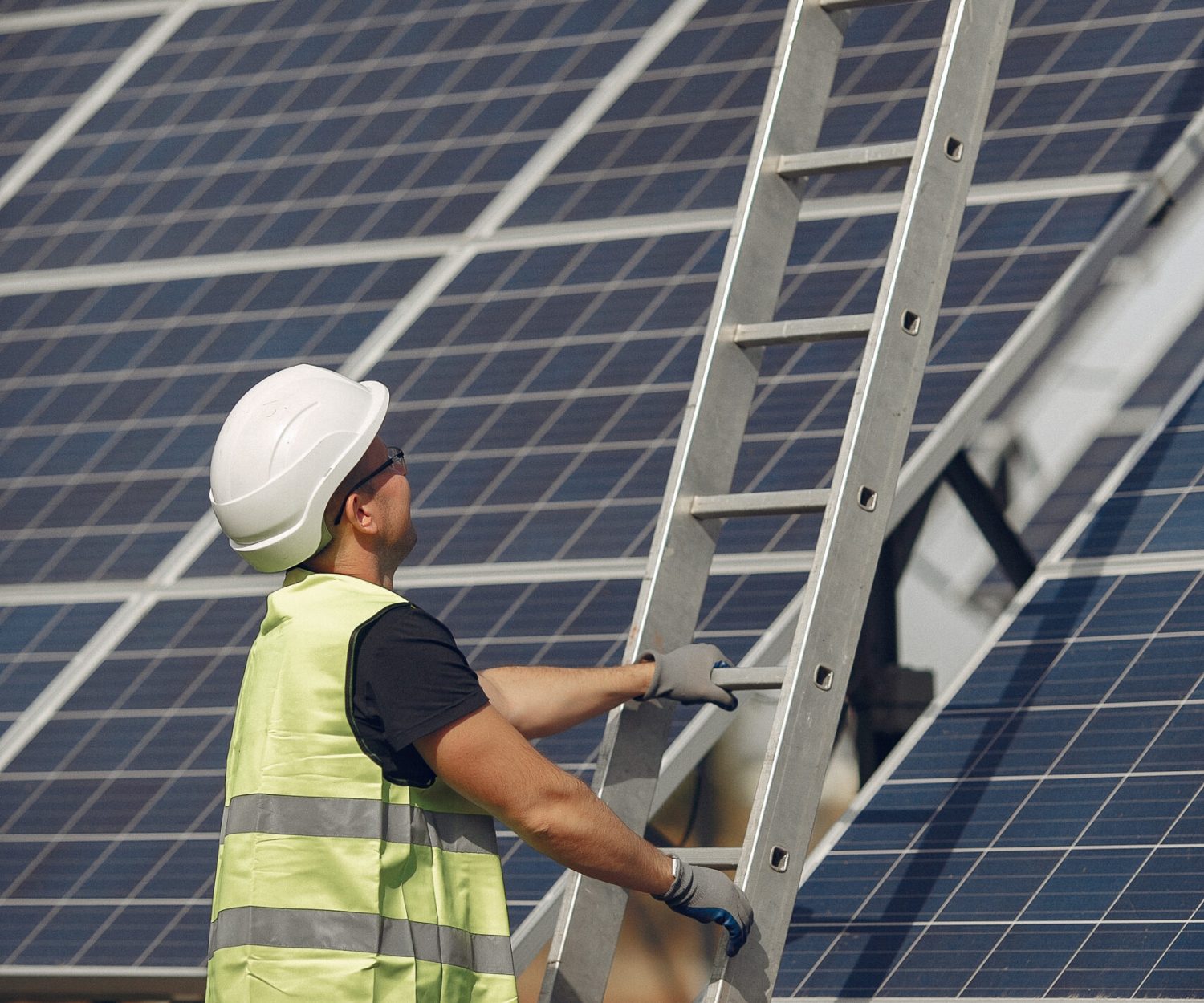 Engineer in a white helmet. Man near solar panel. Worker with a ladder